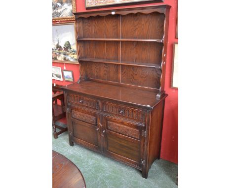 A Jaycee dark oak dresser, two shelves to top, shaped uprights, two monastic fluted short drawers over panelled doored cupboa