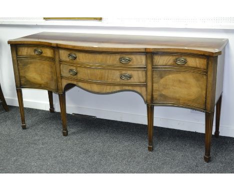 A George III style mahogany bow centre sideboard, fitted with two drawers flanked by cupboard doors, tapering legs.  Mid 20th