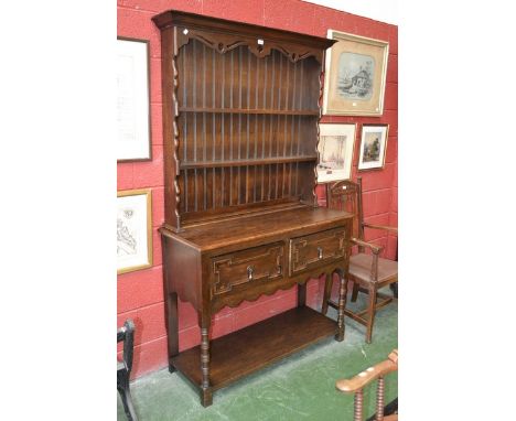 A 20th century Jacobean style dresser, outswept cornice, shaped uprights, two drawers, drop swing handles, shaped skirt, turn