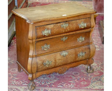 A Dutch oak bombe shaped commode, serpentine top, three graduated drawers, pierced brass escutcheons, ball and claw feet