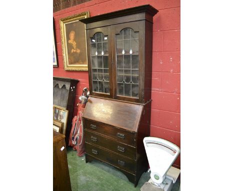 A 1920's oak bureau bookcase, outswept cornice, lead glazed doors to top, fall front over three long drawers to base.
