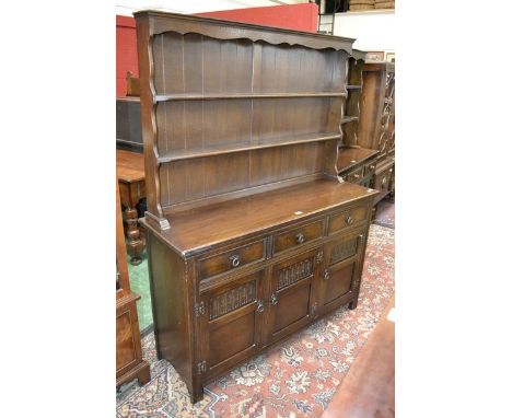 An oak dresser, shaped uprights and two shelves to top, three short drawers over three door cupboard to base, stile feet. 174
