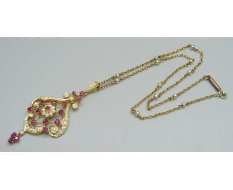 A 15ct gold Art Nouveau drop pendant set with rubies and seed pearls, 5.8cm including bale and drop, on a yellow metal chain 