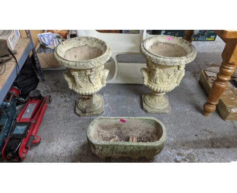 A pair of lightly weathered garden pedestal urns, classical figurative decoration cast in relief with twin handles and fluted