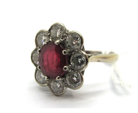 An 18ct White Gold Ruby and Diamond Cluster Ring, oval claw set to the centre, within shaped border of uniform brilliant cut 