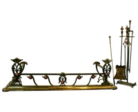An Arts &amp; Crafts period brass fender with stylised motifs surmounted with ceramic roundels, together with associated fire