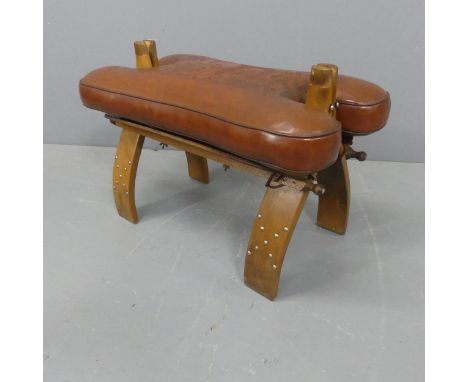 A camel saddle design footstool, with oak base and leather cushion. Width 63cm, height 42cm, depth 37cm.