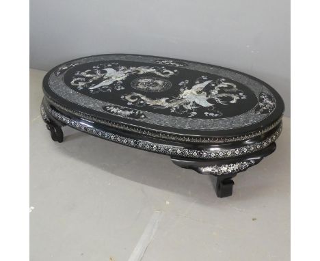 A modern Korean black lacquered oval low coffee table, with inlaid mother-of pearl phoenix decoration. Length 150cm, height 4