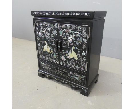 A Korean black lacquered jewellery cabinet, with two doors revealing a drawer fitted interior, a single long drawer and with 