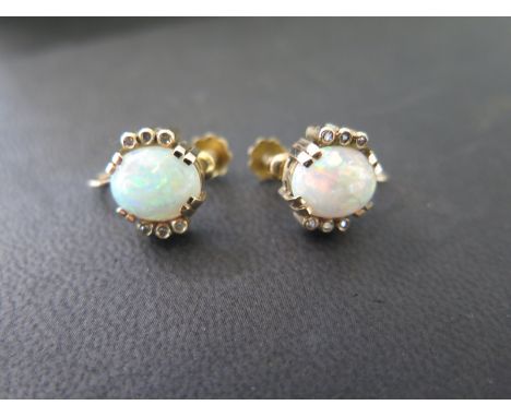 A pretty pair of 9ct gold and opal screw back earrings, centrally set opal approx. 10 x 7mm, flanked either side by three sma