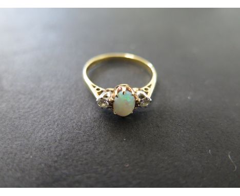 An opal and diamond ring, yellow gold shank and tapered chenier shoulders to a central oval cabachon cut opal flanked by two 