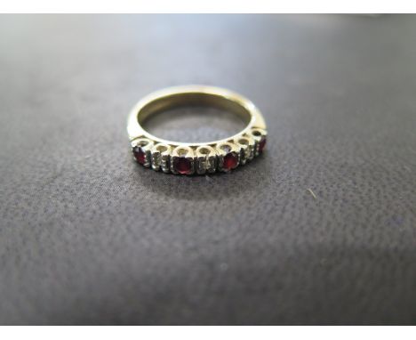 A 9ct yellow gold ruby and diamond set 1/2 hoop ring set with four round mixed cut rubies and three 8 cut diamonds - total di