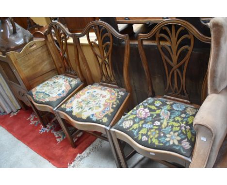 A set of three early 20th Century mahogany dining chairs having wave fronts and drop in tapestry seats, some of moulding loos