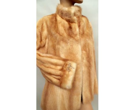 A 1960s mink jacket in pale champagne tones. Jacket features mandarin style collar and has hook fastenings to front, slit sid