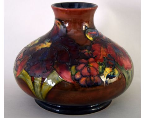 Three pieces of Moorcroft flambe glazed pottery, one a large vase of round squat form in the 'Orchid' pattern, signed and imp