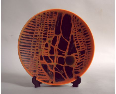 A Poole Pottery Studio plate painted with an abstract design in black on a vivid orange, mark to base 28cm. diam.