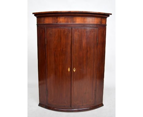 A Regency mahogany and satinwood banded bow fronted corner cabinet, 88cmW