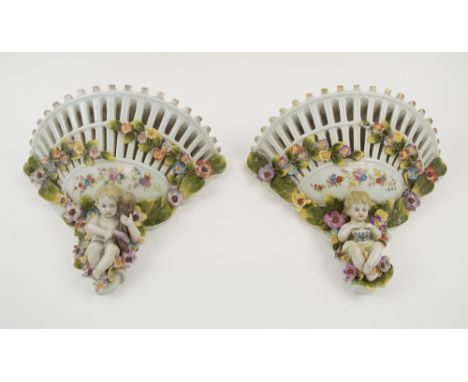 CERAMIC WALL BRACKETS, a pair, decorated flowering sprays and cherubic figures, each 28cm x 25cm H. (2)