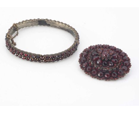 A Bohemian 19th century oval garnet bangle,  the double row of rose cuts, on a white metal base, 5.3 cm by 5.8 cm inner measu