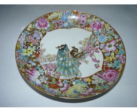 A Chinese saucer Dish, 20th century, finely painted in famille rose enamels with peacocks in pine branches within a millefleu