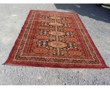 A Bordered and patterned red ground Carpet with four central Guls in geometric pattern, 111" x 79".