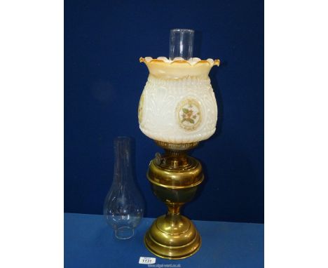 A decorative Oil lamp with spare chimney and white shade.