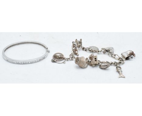 A silver charm bracelet with 9 charms together with a silver CZ bangle (2). 49.4 grams. 