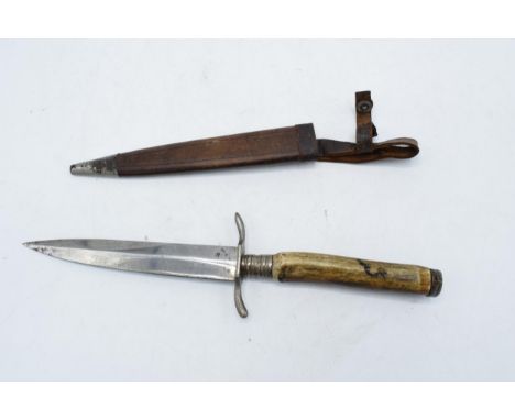 A 20th century blade in the style of a Fairburn Sykes fighting knife with leather scabbard. 28.5cm long from handle to blade.