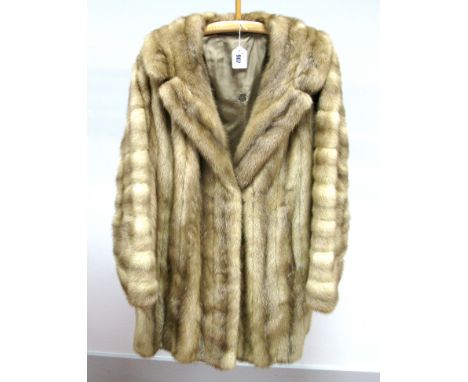 A Light Brown Three-Quarter Length Mink Coat, the bell shaped sleeves with horizontal pelt detail, rever collar, 86cm long.