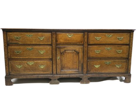 AN 18TH CENTURY OAK DRESSER with central panelled door and drawer, flanked by six graduating drawers, divided by chevron band