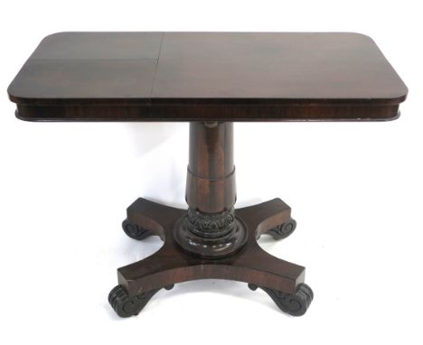 A VICTORIAN ROSEWOOD LIBRARY TABLE the rectangular top set with twin hinged reading slopes and on gun barrel column and quadr