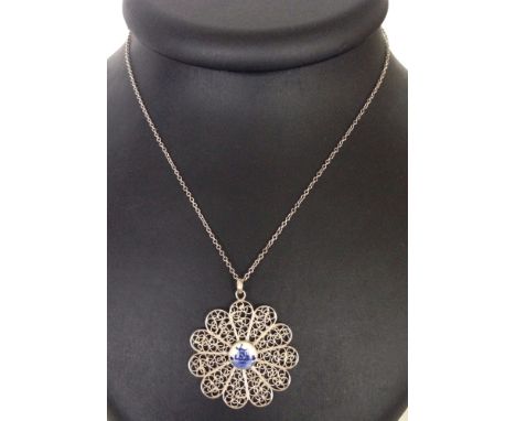 A filigree silver flower design pendant with a ceramic centre depicting a Dutch Delft windmill, 4cm across.