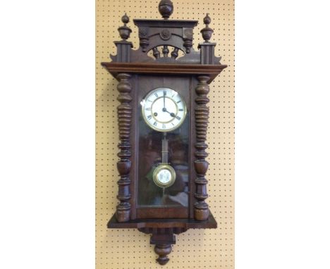 A wooden cased wall clock with enamel dial and pendulum. In working order with key.