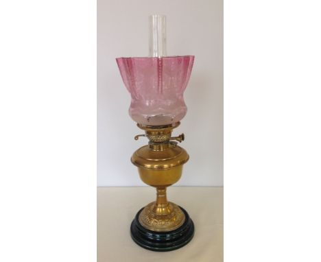 Victorian brass oil lamp on dark green ceramic base with acid etched cranberry glass shade.
