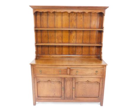 A Georgian style oak dresser, with a two shelf plate rack over two drawers above panelled cupboard doors, raised on square le