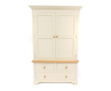 A 19thC style cream painted and light oak linen press, the outswept pediment over two doors opening to reveal a brass hanging