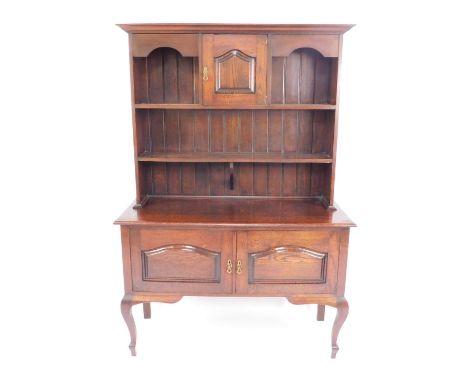 A Victorian oak dresser, the outswept pediment over a single panelled door flanked by recesses over a single shelf plate rack