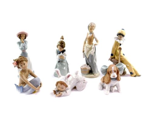 A Lladro porcelain figure of a kneeling girl holding a kitten, together with six Nao figures, some boxed, comprising girl wit