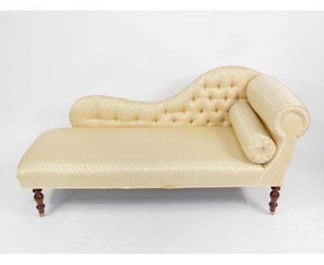 A Victorian style mahogany chaise longue, upholstered in button back gold brocade fabric raised on turned legs, on brass cast