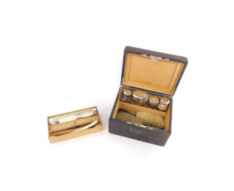 An early 20thC black leather travel case, with a tan leather interior, holding four toilet jars, a toothbrush jar containing 