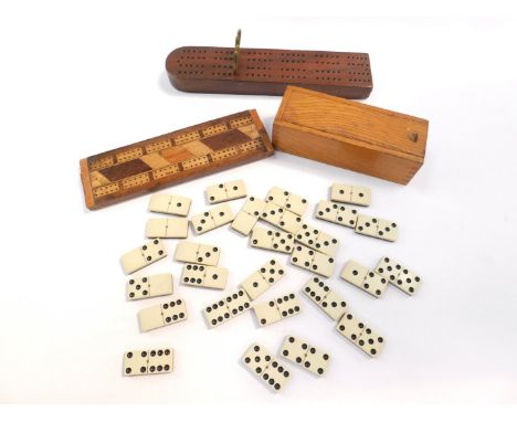 A set of bone and ebony dominoes, oak cased, together with two wooden cribbage boards, one with brass pegs. (3) 