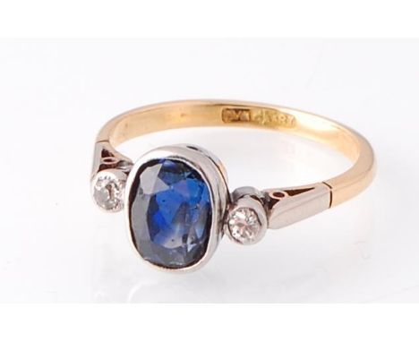 An 18ct gold and platinum sapphire and diamond ring. The central oval cut sapphire ( approx 8mm x 6mm ) with round cut diamon