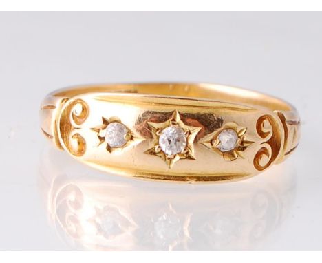 An 18ct gold and diamond ring. The ring set with three diamonds in star cut setting within a scroll end cartouche to stylised