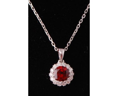 An 18ct white gold garnet and diamond pendant and necklace. The round cut pigeon blood garnet within a halo of diamonds. Tota