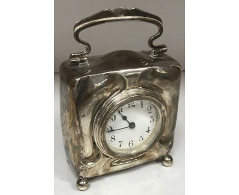 An Edwardian Art Nouveau style silver cased desk clock with swing handle on four ball feet, the movement with circular enamel