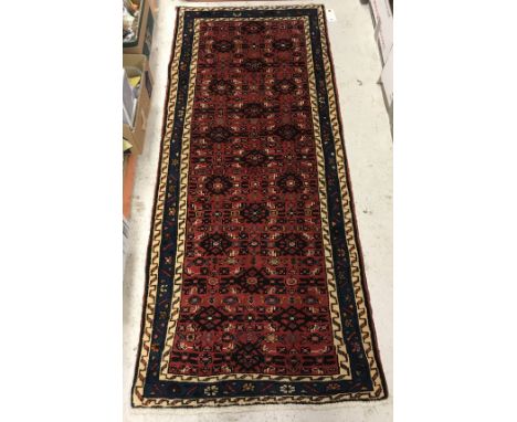 A Persian runner, the central panel set with repeating stylised tarantula motifs on a red ground, within a scrolling blue and