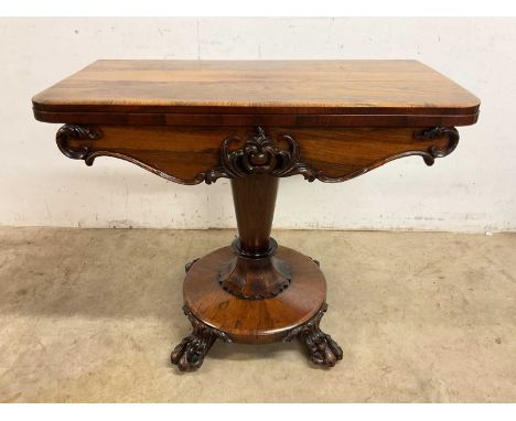 A Victorian rosewood card table with twist and fold out top to inset red baize, carved frieze to tapered pedestal, circular b