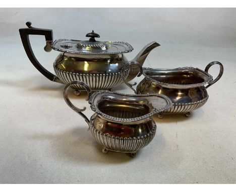 A George V hallmarked silver three piece tea service of part gadrooned detail, London 1915 and 1916, length of teapot 29.5cm,