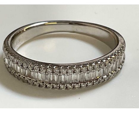 A 14ct white gold and diamond half eternity ring with central row of baguette cut stones flanked by borders of round brillian