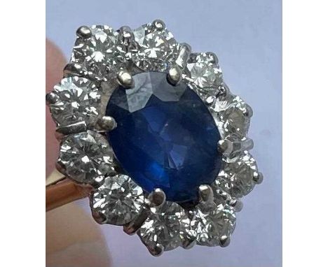 A good yellow and white metal diamond and sapphire oval cluster ring with central oval sapphire set within a border of 10 rou